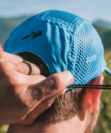 Person wearing a blue elite crusher hat from Headsweats with a blurred natural background
