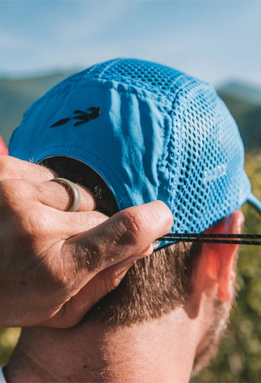 Person wearing a blue elite crusher hat from Headsweats with a blurred natural background