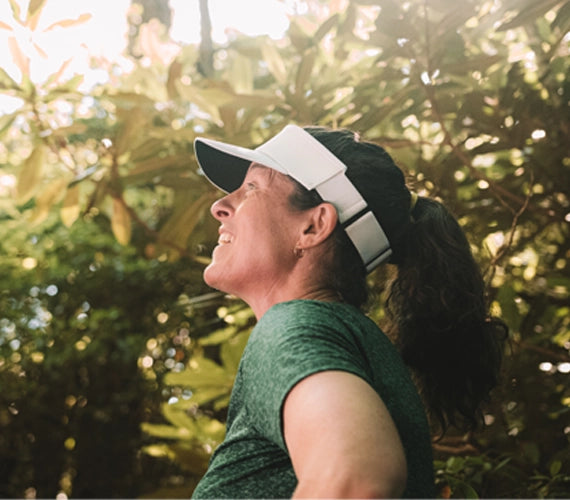 Person wearing an elite visor and green shirt outdoors with trees in the background