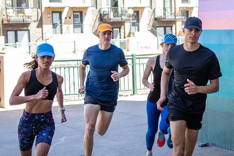 Group of people running outdoors on a city street wearing Headsweats running hats.