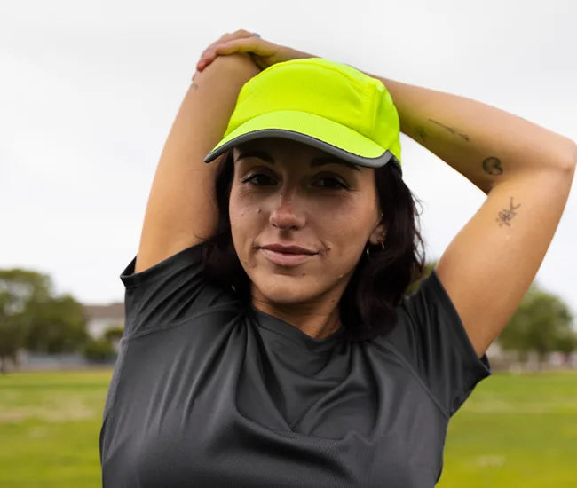 Person wearing a bright yellow reflective running hat from Headsweats and dark shirt outdoors