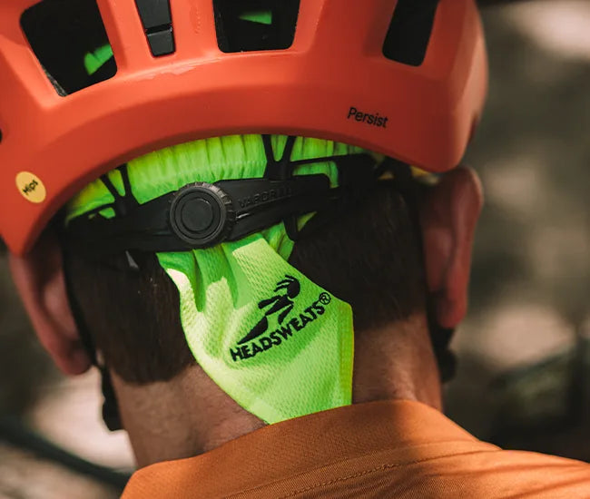 Close-up of a person wearing a red helmet with a green super shorty from Headsweats.